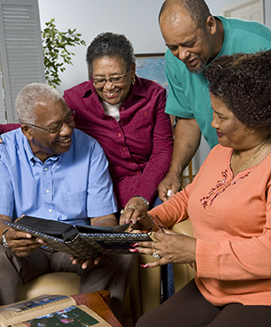 Two men and two women in living room looking at family photos.